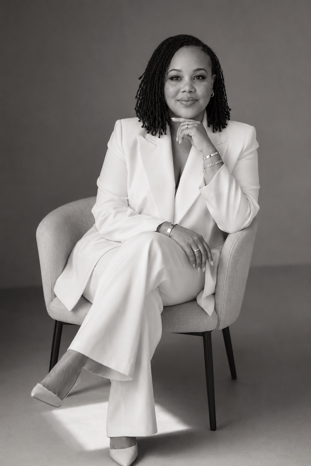Portrait of the Boss Suite founder seated in a white suit.